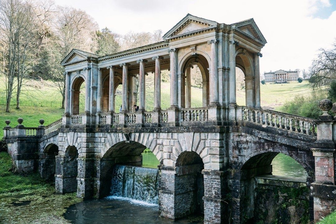 Klassieke stenen brug met zuilen boven een vijver in een kasteelpark